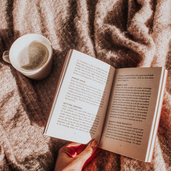 Open book next to a cup of coffee on a blanket